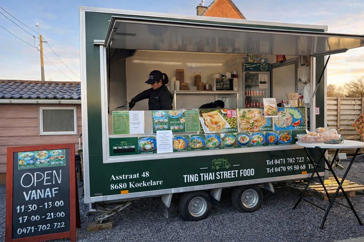 Green food truck with open service window displaying colorful menu boards, worker inside, parked with red OPEN sign visible
